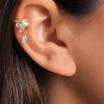 An on-ear lifestyle photograph showcasing a unique, modern statement stud earring finished in a polished silver color, featuring an elongated, curved design encrusted with a dense mosaic cluster of round brilliant and marquise-cut clear crystals that climbs gracefully along the lower earlobe