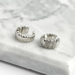 Rhodium-plated chunky ear cuffs featuring a voluminous dome shape with vertical ribbed texture and a central section of shimmering micro-pavé crystals