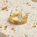 18k gold-tone wide-profile ear cuff featuring three parallel rows of micro-pavé crystals anchored by a prominent, vertically-set oval solitaire stone