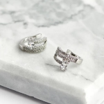 Rhodium-plated wide ear cuff featuring three tiered rows of micro-pavé crystals and a central, vertically-set oval solitaire stone