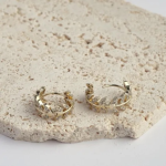 18k gold-tone huggie hoop earrings featuring an intricate, botanical-inspired vine design with marquise-shaped pavé crystal leaves
