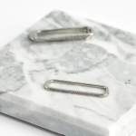 Rhodium-plated elongated oblong ear cuffs featuring a minimalist geometric frame with a delicate partial row of shimmering micro-pavé crystals
