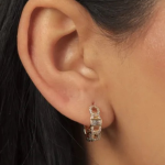A pair of gold-tone huggie hoop earrings featuring a sophisticated chain-link design with a central baguette-cut clear crystal and surrounding pavé-set stones