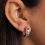 Sleek silver-tone huggie hoop earrings featuring a modern, vertically ribbed texture