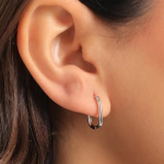 A model wearing a medium-sized, minimalist silver-colored hoop earring with a smooth, polished oblong rectangular silhouette