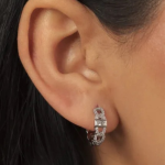 A pair of sleek, silver-tone huggie hoop earrings featuring a fluid, interlocking chain-link design