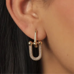A pair of polished gold-tone huggie hoop earrings featuring four aligned, brilliant-cut clear crystals set along the front-facing arc